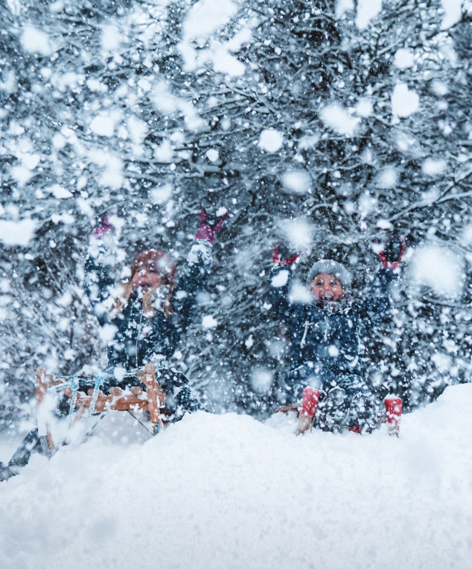 Kinder beim Schlittenfahren im Schnee